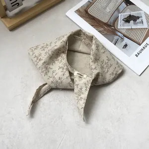 Detail shot of the 100% linen label and vintage floral pattern on a triangle scarf