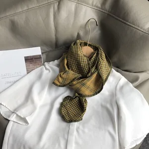 Detail of soft cotton plaid neck scarf in yellow and green over a white blouse