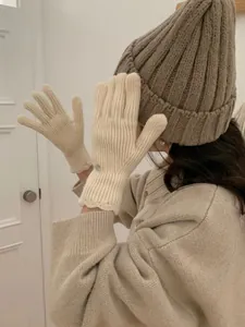 Detail of cream knit gloves with wavy cuffs and decorative buttons for winter warmth