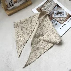 Detail of 100% linen floral triangle scarf showing beige fabric and laundry care label