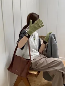 Detailed shot of two-tone knit touchscreen gloves paired with a brown leather tote bag