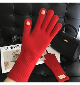 Detail von roten Wollstrickhandschuhen mit Touchscreen-Öffnung an Daumen und Zeigefinger
