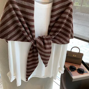 Primer plano de un chal de lana a rayas marrones sobre una camisa blanca de estilo francés