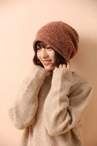 Detailed knit texture of orange and grey mixed wool beanie on a model wearing a sweater