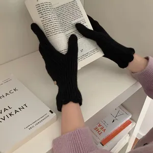 Detail of black knit gloves showing the elegant wavy edge design on the wrist cuffs
