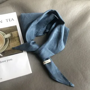 Detail of 100% pure linen navy blue scarf with label on elegant leather background
