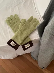 Detail of avocado green knitted touchscreen gloves with brown cuffs and woven label