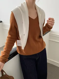 Detalle del chal de lana marfil y jersey de punto marrón con cuello en V para mujer