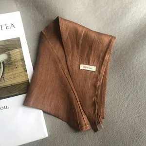 Detail shot of terracotta 100% linen scarf showing natural fabric texture and care label