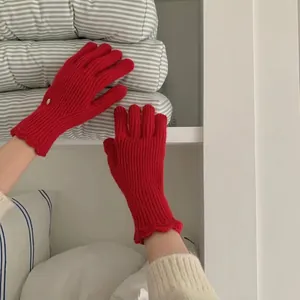 Detail of red cable knit gloves showing wave-edge cuff and warm thick wool texture
