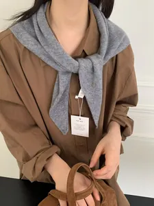 Detalle del pañuelo triangular de punto gris con bolso de mano en ante marrón