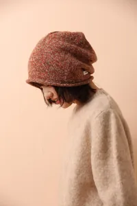 Close-up of orange mixed knit wool beanie with white label and soft texture