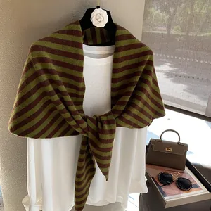 Detalle de bufanda de lana a rayas sobre una blusa blanca con accesorios elegantes