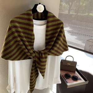 Detalle de la bufanda triangular de lana a rayas oliva y marrón con punto de calidad