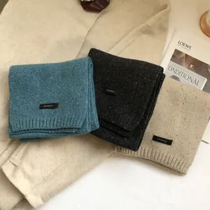 Close-up of stacked 100% wool knit scarves in blue and grey with soft ribbed texture