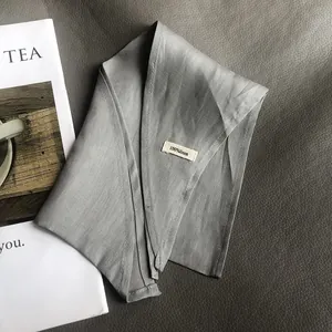 Detail of grey linen fabric showing neat stitched edges and a 100% linen material label