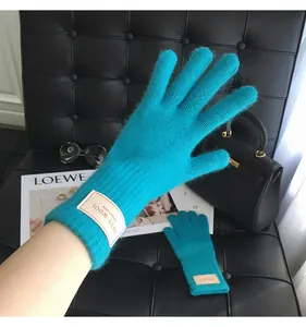 Details von Strickhandschuhen aus Wolle in Pfauenblau mit Rippbündchen auf Lederhintergrund