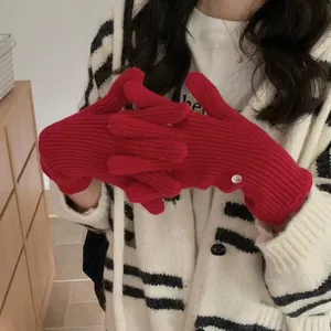 Close-up of red knitted winter gloves with rib-knit texture and white button detail