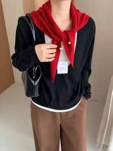 Detalle de un pañuelo triangular de punto 50% lana usado como elegante chal rojo para hombros
