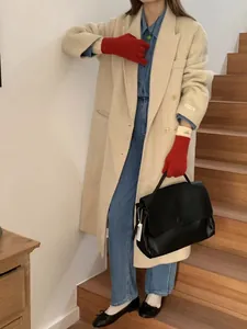 Detail of red knit touchscreen gloves paired with an oversized beige wool overcoat