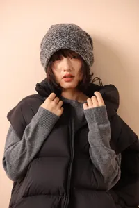 Close-up of a grey knit wool beanie worn by a model with a black vest for winter style