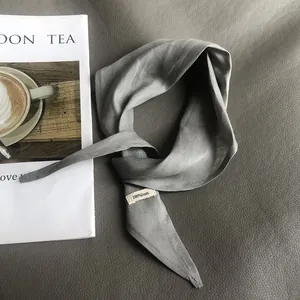 Detailed view of grey 100% linen scarf with material label on premium leather background