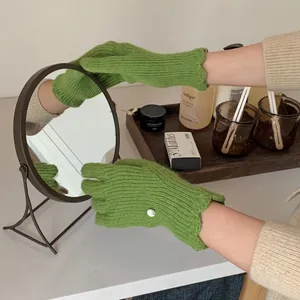 Green knit glove detail showing ribbed texture, decorative button and wavy cuff edge