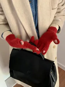 Detail of red ribbed knit fingerless gloves with white trim worn with a white coat