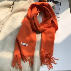 Detail of orange 100% Australian wool scarf showing soft texture and premium material label