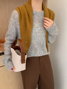 Detalle del bolso tipo saco de lona beige con asas de cuero marrón y hebillas