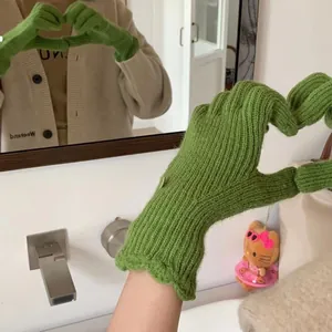 Detail of green knitted winter gloves with touchscreen tips and cute button decoration