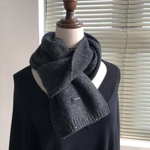Detail view of charcoal grey 100% wool knitted scarf with white speckled pattern