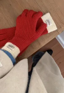 Detail of red and cream knitted winter gloves with touch-screen tips on wooden surface