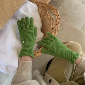 Detail showing the grass green knitted wool glove with ribbed texture and scalloped cuff