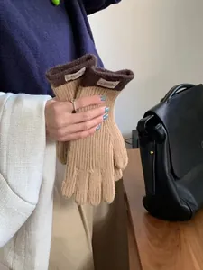 Detail of beige knitted gloves with dark brown cuffs and stylish woven label branding