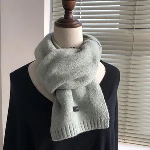 Detail of light green tweed wool scarf with colorful flecks and a square black label