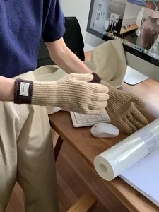 Detail of touchscreen knitted gloves in khaki and brown, shown in an office setting