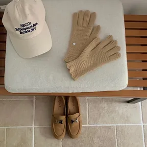 Flat lay of warm khaki knit gloves with a beige embroidered cap and suede loafers