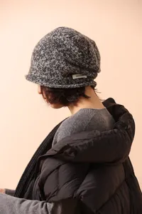 Detailed view of grey mixed knit wool hat with a white 100% WOOL label on the side