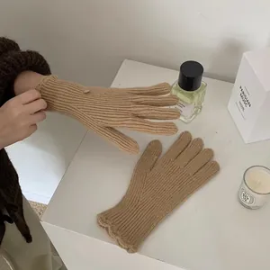Close-up of khaki ribbed knit gloves with ruffled cuffs and metallic button detail