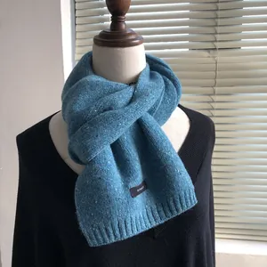 Detailed texture of blue 100% wool knit scarf with starry white speckles on black sweater