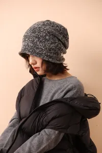 Close-up of a chunky knit wool beanie in charcoal grey with a white woven side label