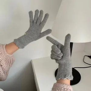 Detailed view of grey rib-knitted touchscreen gloves with wavy edge and metal button detail