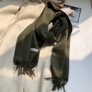 Detail of 100% Australian wool label on dark green scarf with soft fringe accents