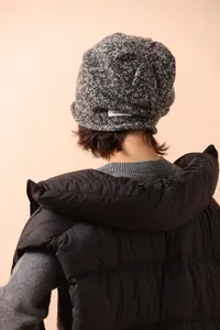 Detail showing the 100% wool material label on a speckled knit beanie hat for winter