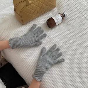 Close-up of grey knit gloves with ribbed texture and decorative scalloped wave cuffs