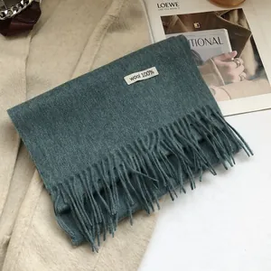 Close-up of 100% Australian wool scarf featuring long fringe and a dark cyan-blue texture