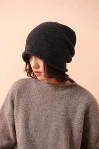 Close-up of dark grey wool knit beanie with colorful tweed texture and rolled edge detail