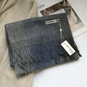 Detail eines 100 % Wollschals mit Fransendesign und grau-blauem Patchwork-Muster