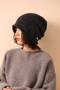 Detail of grey wool beanie with colorful flecks and white woven label on model